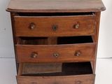 a small wooden chest of drawers on a white wall