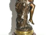 bronze statue of a woman sitting on a rock on a marble base