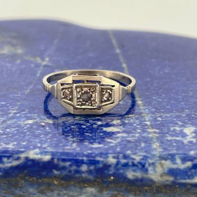 une image représentant une bague en diamant posée sur une pierre bleue