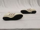 pair of white sneakers with black soles sitting on a white surface