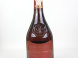 an old bottle of wine sitting on top of a white table