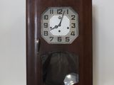 une horloge en bois accrochée au mur, près du mur