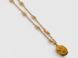 a gold necklace with a coin on a chain