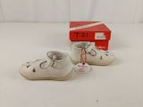 pair of white baby shoes with a red box on a white surface