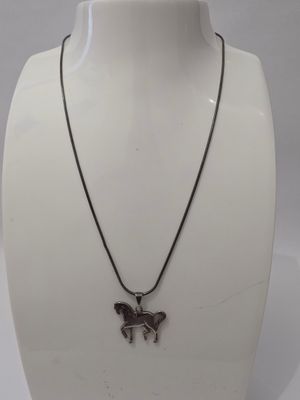un gros plan d'un collier porté par un mannequin, orné d'un cheval