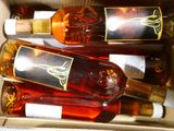 Plusieurs bouteilles de vin se trouvent dans une boîte sur laquelle sont apposées des étiquettes.