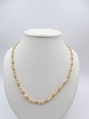 a gold beaded necklace on a mannequin neck