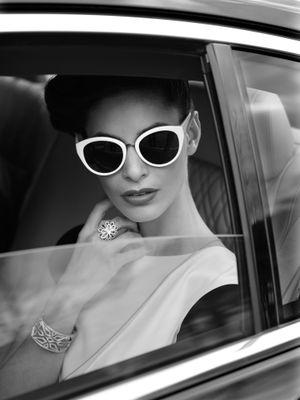 photo en noir et blanc d'une femme portant des lunettes de soleil, assise dans une voiture