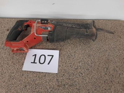 une perceuse filaire rouge posée par terre à côté d'un panneau