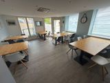 many tables and chairs in a room with a clock on the wall