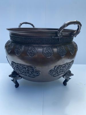 un pot antique en bronze muni d'anses et posé sur un socle