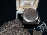 a silver purse and a silver pocket watch sitting on a table