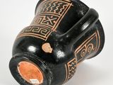 a black vase with a design on it on a white surface