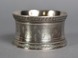 an antique silver napkin ring on a table with a gray background