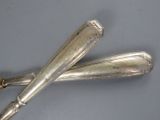 two silver spoons on a gray surface with a wooden handle