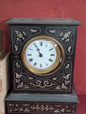 une horloge noire et dorée posée à côté d'une pile de livres