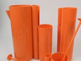 an orange pitcher, a cup, and a set of utensils