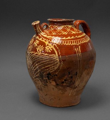 a brown vase with a bird on it on a gray surface