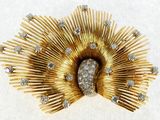 a gold brooch with diamonds on it on a white surface