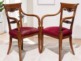 two wooden chairs sitting on top of a white rug in a living room