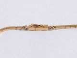 a close up of a gold bracelet on a white surface