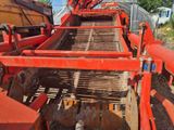une machine rouge qui est à l'arrêt dans la poussière