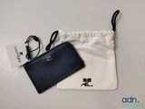 un portefeuille noir et blanc et un sac blanc posés sur une table