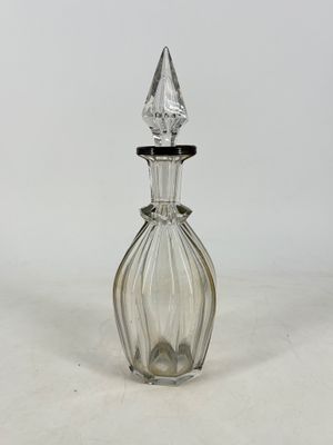 clear glass perfume bottle with a pointed top on a white surface