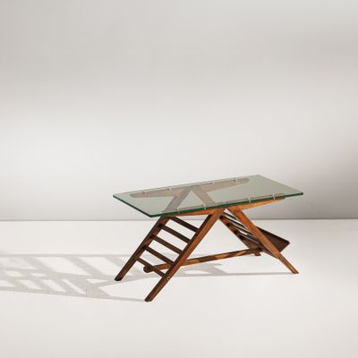 une table en verre avec des pieds en bois et un plateau en verre, posée sur un sol blanc
