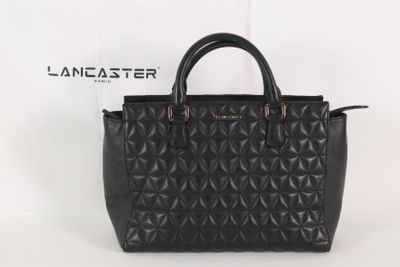 un sac à main noir posé sur une boîte blanche