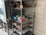 Plusieurs plateaux de nourriture sont posés sur un chariot métallique dans une cuisine
