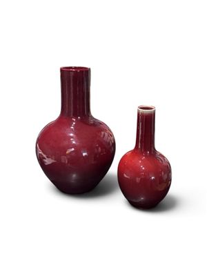 deux vases rouges posés l'un à côté de l'autre sur une surface blanche