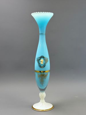une image représentant un vase bleu orné d'une bordure dorée, posé sur un socle blanc