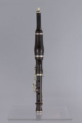a close up of a clarinet on a clear surface with a gray background