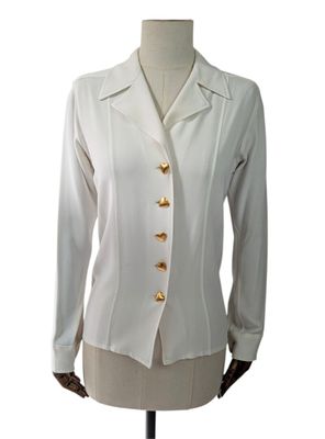 La femme porte une veste blanche ornée de boutons dorés.