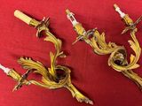 pair of antique brass wall sconces on a red cloth