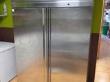 a stainless steel refrigerator in a kitchen with a green wall