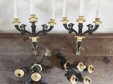 two black and gold candelabs with white candles on top of a wooden table