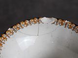 a close up of a white bowl with orange designs on it