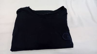 un t-shirt noir posé sur une surface blanche, avec un fond blanc