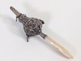 a small silver object with a wooden handle on a white surface