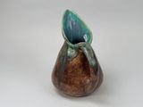 a brown and blue vase sitting on a white surface