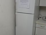 a white refrigerator in the corner of a kitchen with a sign on it