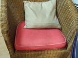 une chaise en osier sur laquelle est posé un coussin, dans une pièce