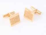 a pair of gold cufflinks on a white background