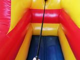 a person holding a stick in front of an inflatable bouncer
