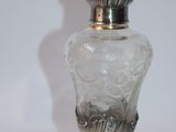 a glass bottle with a silver lid on a white surface
