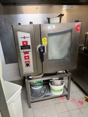 un four professionnel dans une cuisine professionnelle, avec un seau de peinture posé par terre à côté