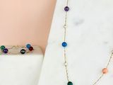 a close up of a necklace with multi colored beads on a marble surface