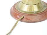 a small brass bell on a wooden base with a cord